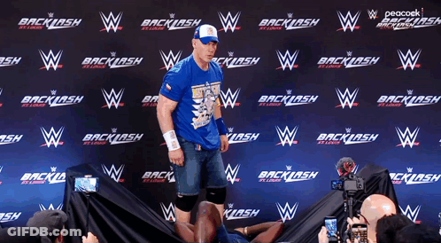 Man In Blue Shirt In Front Of Backlash Wall GIF