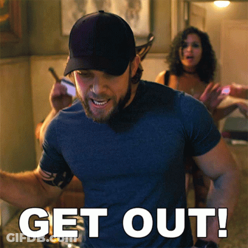 Man In Blue Shirt In Front Of Get Out Sign GIF