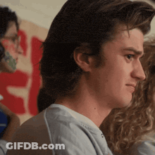 Man In Blue Shirt In Front Of S Sign GIF