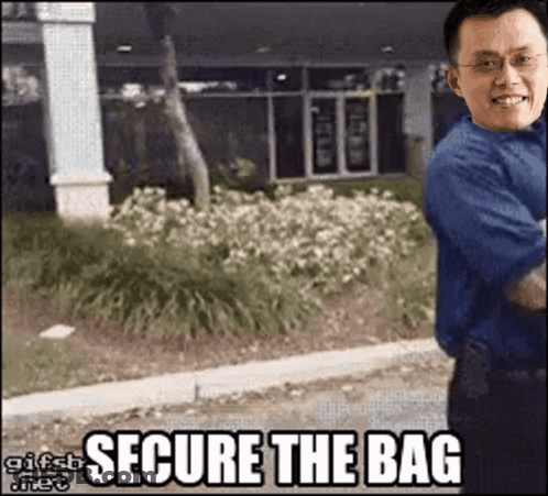Man In Blue Shirt In Front Of Secure The Bag Building GIF