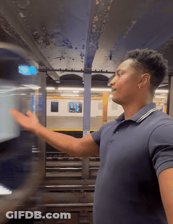 Man In Blue Shirt In Front Of Subway Train GIF