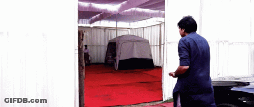 Man In Blue Shirt In Front Of Tent GIF