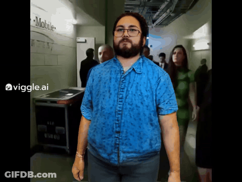 Man In Blue Shirt In Hallway With Mobile Sign GIF