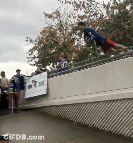 Man In Blue Shirt Jumping Over Juice Sign GIF