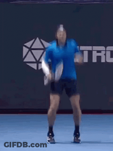 Man In Blue Shirt Jumping With Tennis Racquet GIF