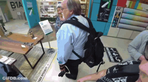 Man In Blue Shirt Kneeling Before Fabric Specialty Sign GIF