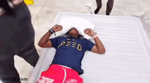 Man In Blue Shirt Laying On Bed With Pillow Over Head GIF