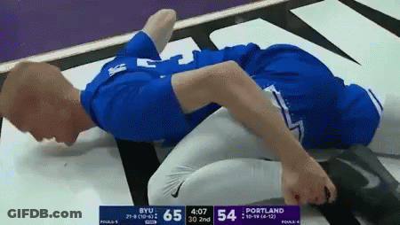 Man In Blue Shirt Laying On Ground During BYU Vs Portland Wrestling Match GIF
