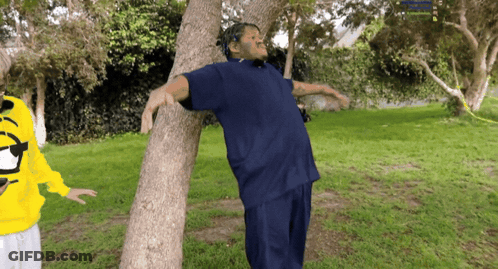 Man In Blue Shirt Leaning Against Tree GIF
