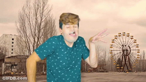 Man In Blue Shirt Making Face In Front Of Ferris Wheel GIF