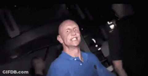 Man In Blue Shirt Making Funny Face In Dark Room GIF