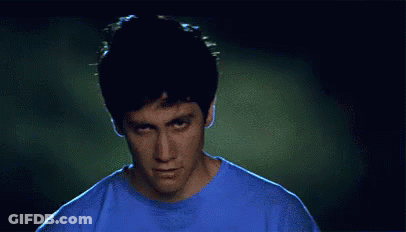 Man In Blue Shirt Making Funny Face In Dark Room GIF