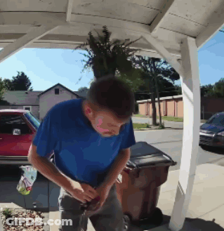 Man In Blue Shirt Next To Brown Trash Can GIF