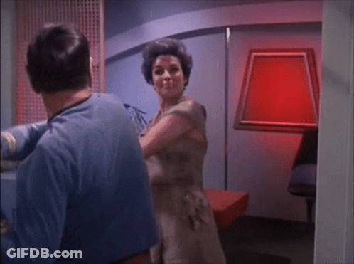 Man In Blue Shirt Next To Woman In Brown Dress GIF