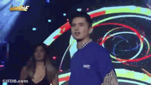 Man In Blue Shirt On Stage With Woman In Black Dress GIF