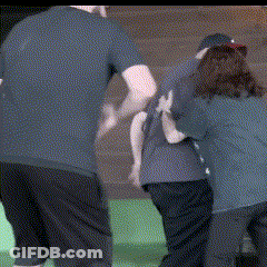 Man In Blue Shirt Pushing Woman In Black Shirt GIF