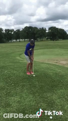 Man In Blue Shirt Putting Golf Ball On Course With TikTok Logo GIF