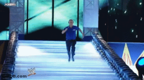 Man In Blue Shirt Running Down Ramp With WWE Logo GIF