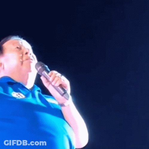 Man In Blue Shirt Singing Into Microphone With Letter S GIF