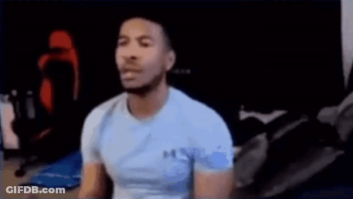 Man In Blue Shirt Sitting At Computer On Bed GIF
