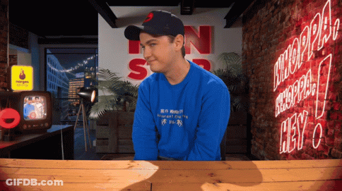 Man In Blue Shirt Sitting At Neon Hey Sign GIF