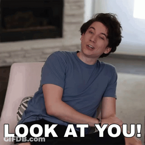 Man In Blue Shirt Sitting By Fireplace Saying Look At You GIF