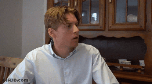 Man In Blue Shirt Sitting By Wooden Cabinet GIF