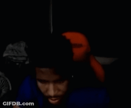 Man In Blue Shirt Sitting In Dark Room With Stuffed Animal GIF