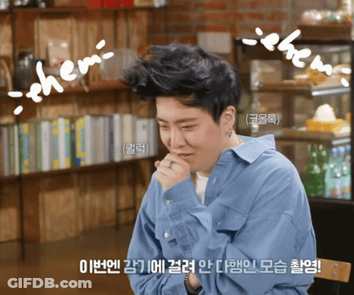 Man In Blue Shirt Sitting In Front Of Bookshelf With Chem On Head GIF