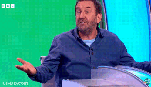 Man In Blue Shirt Sitting In Front Of Green Screen With BBC GIF
