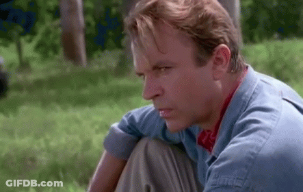 Man In Blue Shirt Sitting In Grass Looking GIF