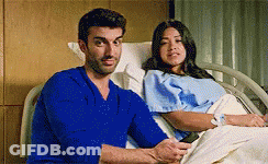 Man In Blue Shirt Sitting Next To Woman In Hospital Bed GIF