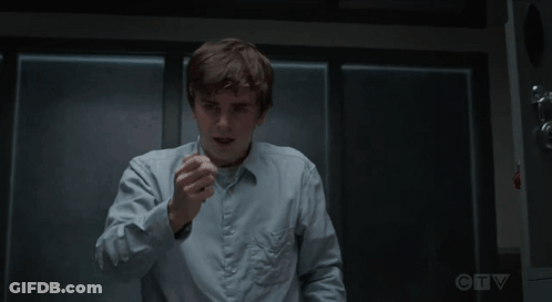 Man In Blue Shirt Sitting With Hands Folded In Dark Room GIF