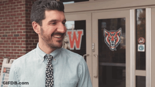 Man In Blue Shirt Smiling In Front Of Building With W GIF