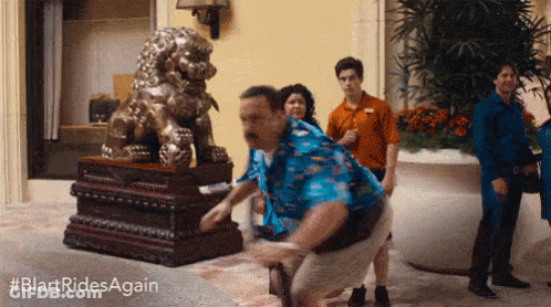 Man In Blue Shirt Squatting In Front Of Lion Statue GIF