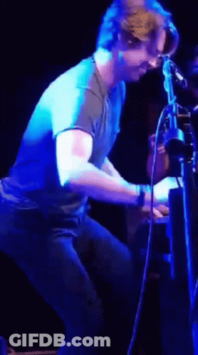 Man In Blue Shirt Standing Before Purple Light GIF