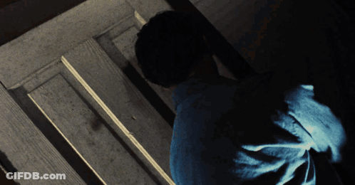 Man In Blue Shirt Standing In Dark Room GIF