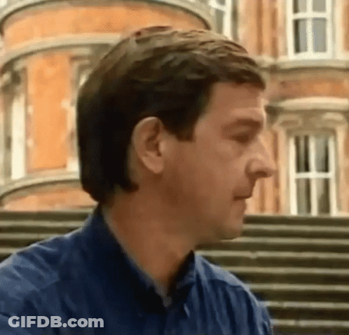 Man In Blue Shirt Standing In Front Of Building GIF