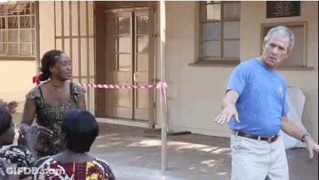 Man In Blue Shirt Standing In Front Of Building With Sign GIF