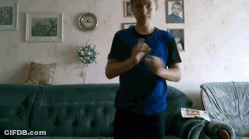 Man In Blue Shirt Standing In Front Of Couch GIF