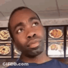 Man In Blue Shirt Standing In Front Of Menu GIF