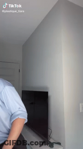 Man In Blue Shirt Standing In Front Of TV With TikTok Watermark GIF
