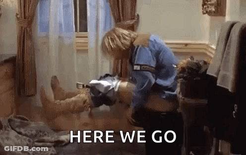 Man In Blue Shirt Standing Next To Man Laying On Bed GIF
