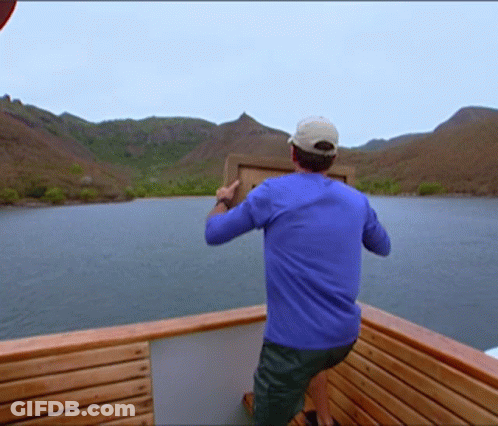 Man In Blue Shirt Standing On Boat Holding Box GIF
