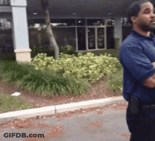 Man In Blue Shirt Standing On Sidewalk GIF