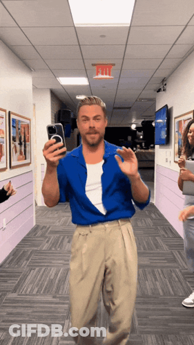 Man In Blue Shirt Taking Selfie Under Exit Sign GIF