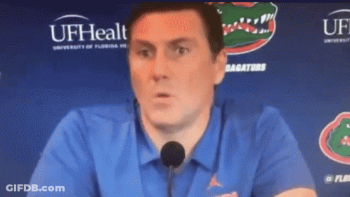 Man In Blue Shirt Talking Into Microphone At UFHealth Sign GIF