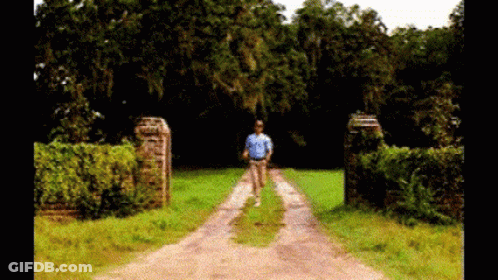 Man In Blue Shirt Walking Down Dirt Road GIF
