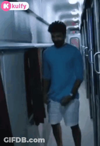 Man In Blue Shirt Walking Down Hallway With Kulfy Logo GIF