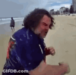 Man In Blue Shirt Walking On Beach GIF